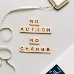 Motivational concept with scrabble tiles spelling no action no change alongside a measuring tape and scale.
